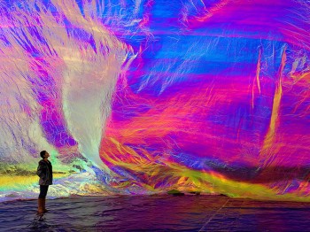 A person stands next to a large, brightly colored piece of material which surrounds the space.