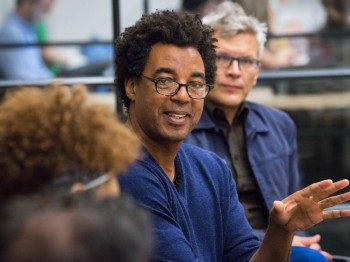 A man speaks at a table with a group of people.