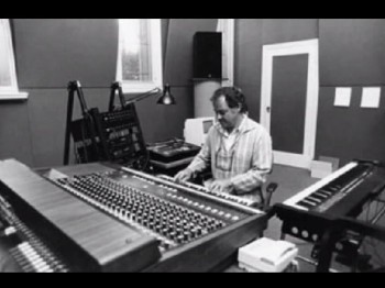 A man plays a keyboard in a music production studio.