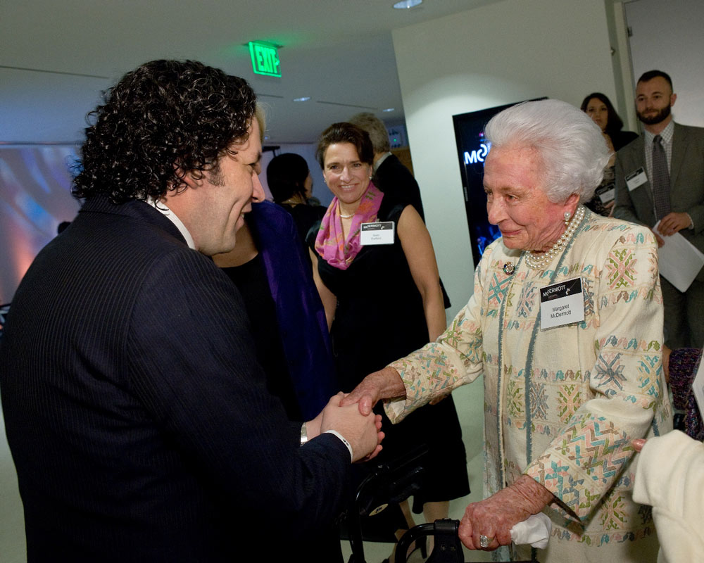 A man and woman shake hands as other people look on