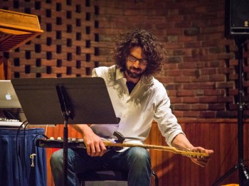 A man sitting at a music stand tunes a guitar.