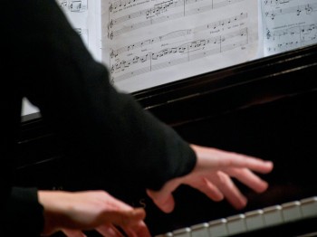 Hands playing a piano.