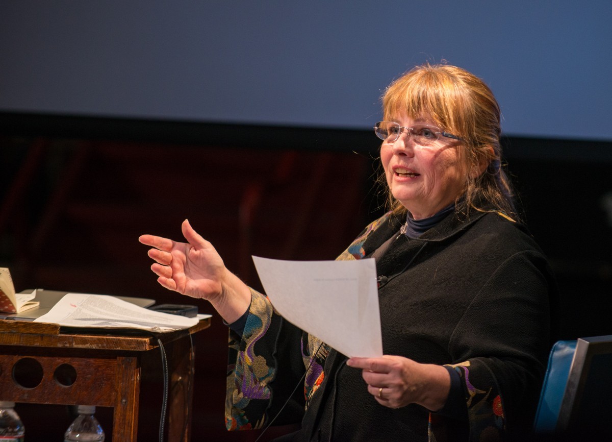 A woman speaks holding a piece of paper.