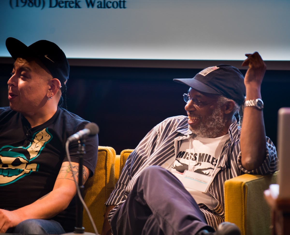 Two men in chairs on stage at a symposium.