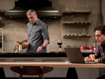 Two actors perform in a kitchen set.