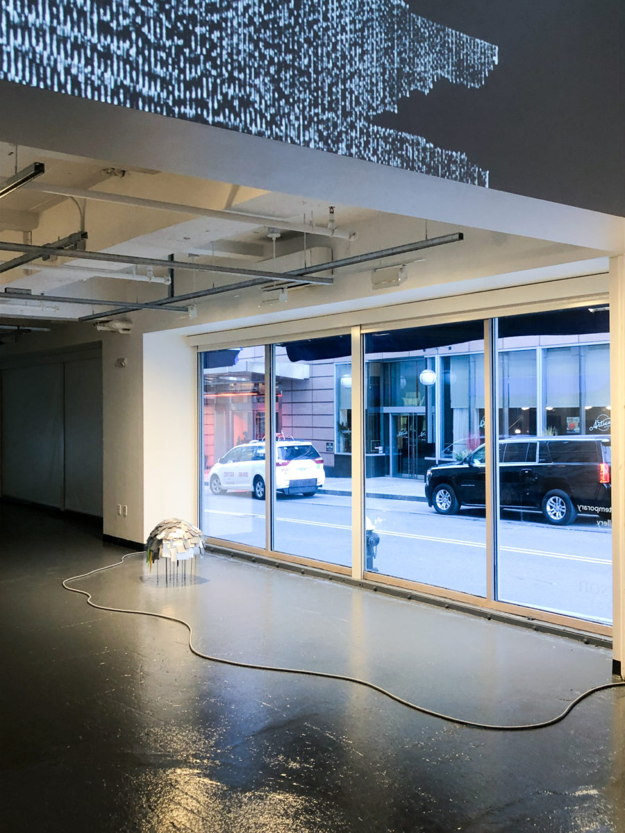 Nicole L'Huillier's sculpture moves in front of a large gallery window as cars pass outside.