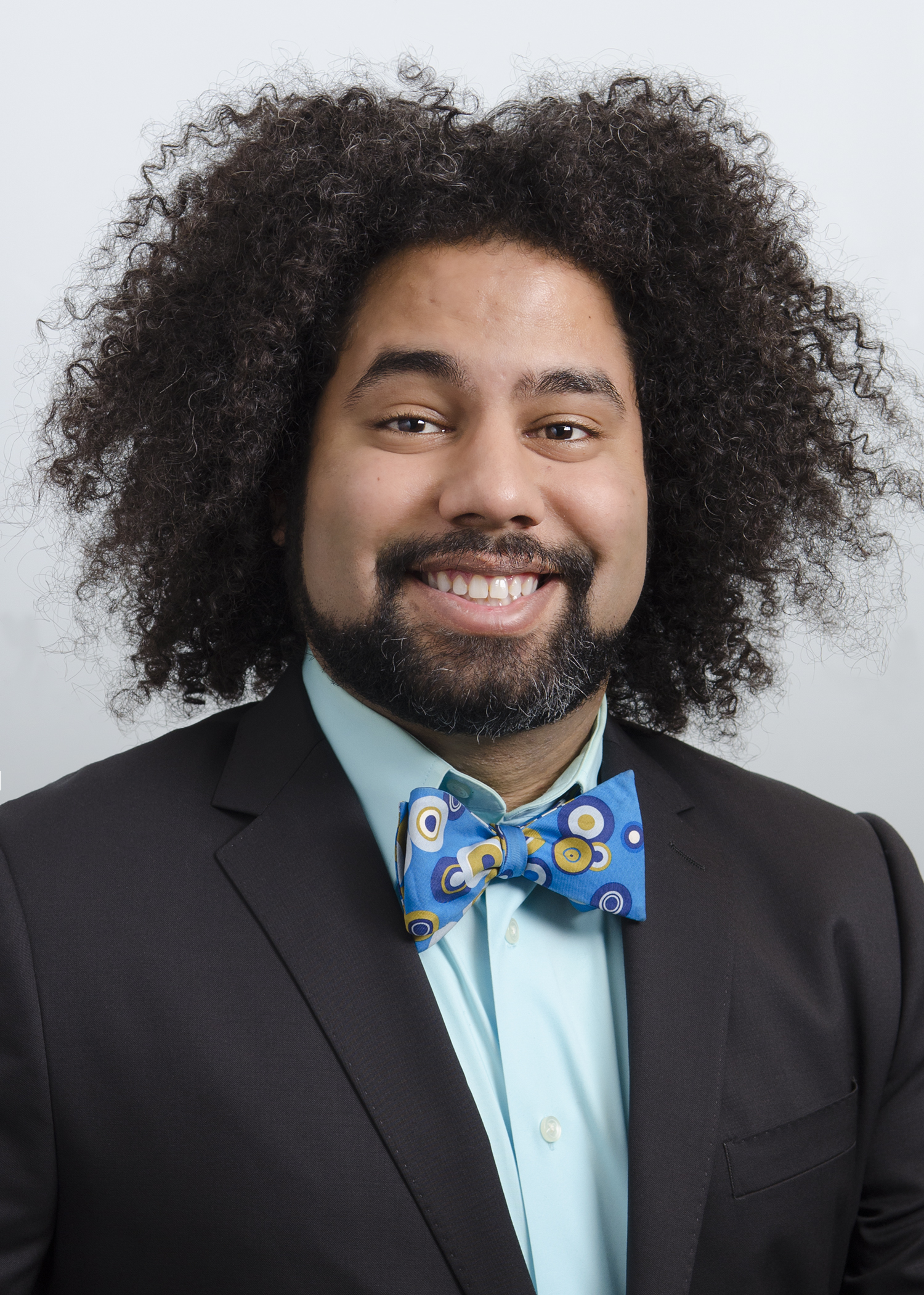 Daniel Chonde smiles directly at the camera while wearing a colorful bowtie and suit jacket.