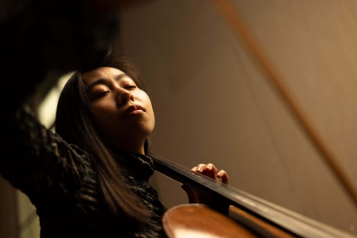 Woman playing cello with eyes closed, seen from below