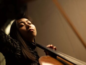 Woman playing cello with eyes closed, seen from below