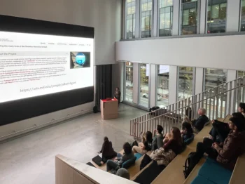 Albert Figurt presents his project on a big screen to a group seated on bleachers.