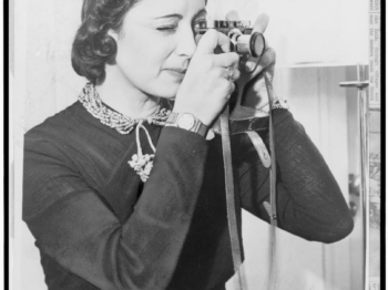 black and white photograph from 1937 of a woman looking through the viewfinder of a film camera